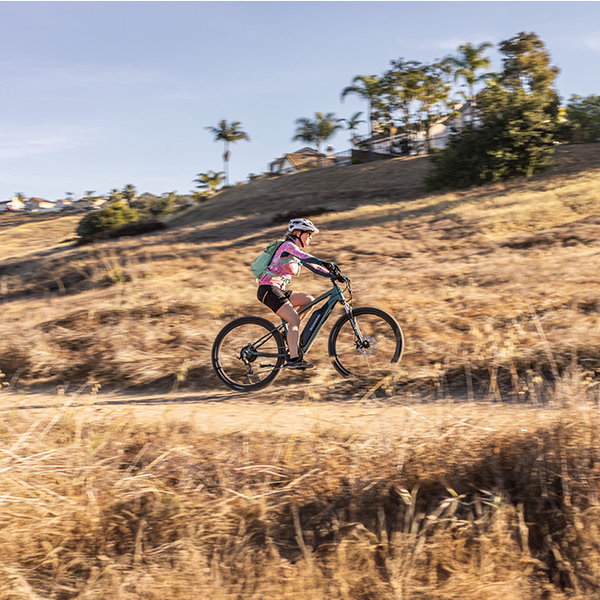 A woman riding her Schwinn e-bike up a gravel trail.